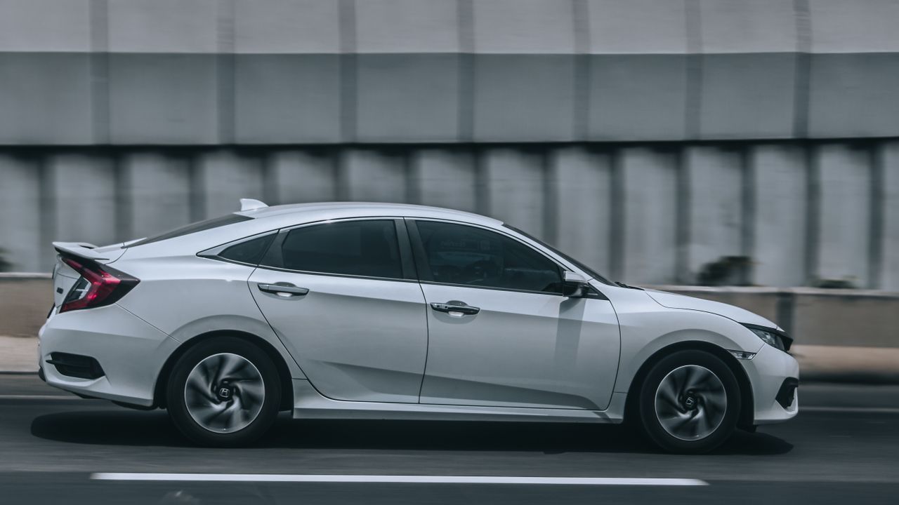 A sleek white car speeding down an urban road, illustrating motion and style.